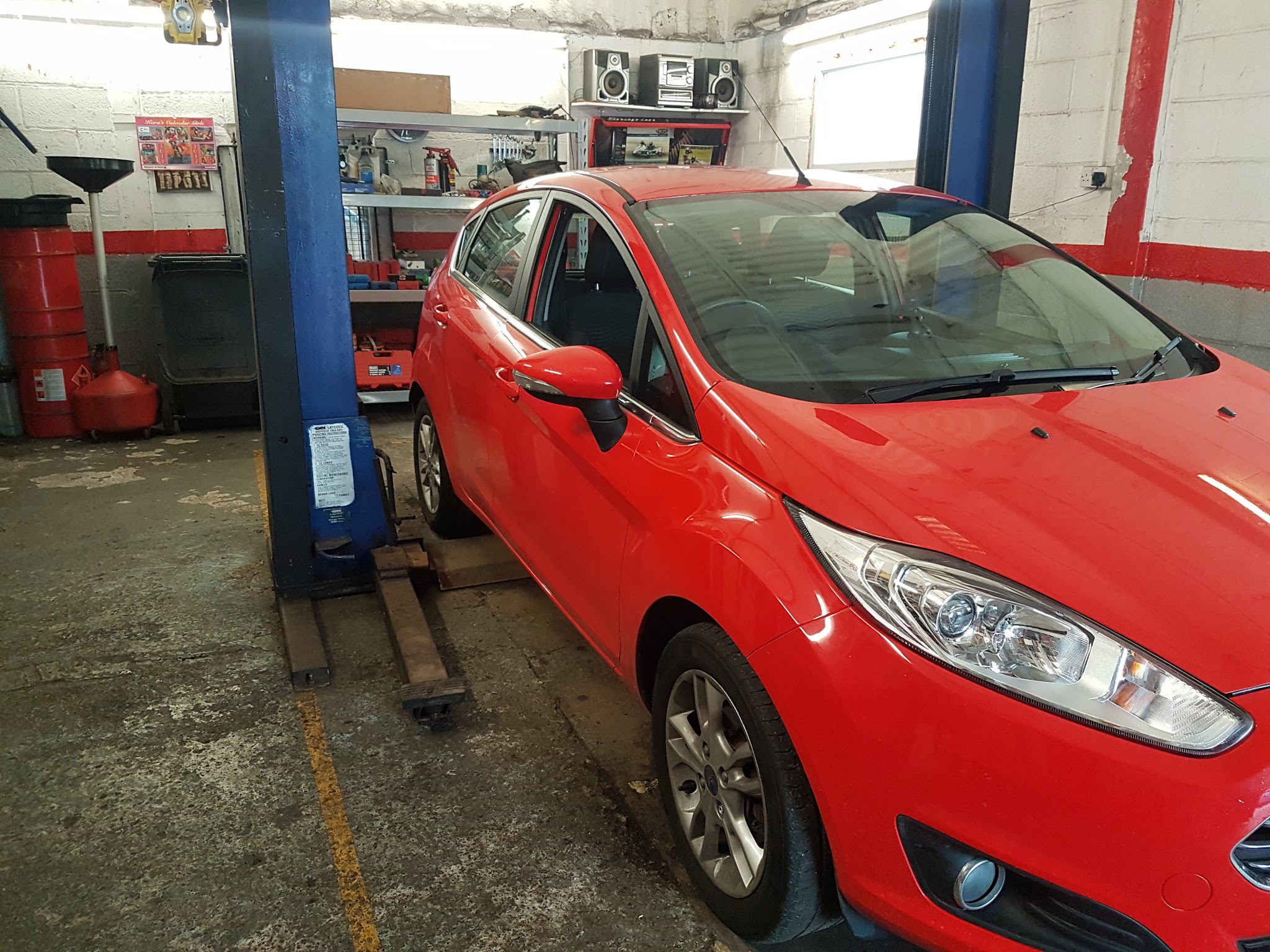 A red Ford Fiesta on the two-post lift inside the Autoz workshop